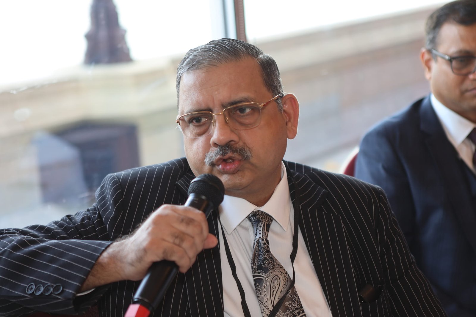 A delegate speaks during the round-table lunch, Westminster visible through the window