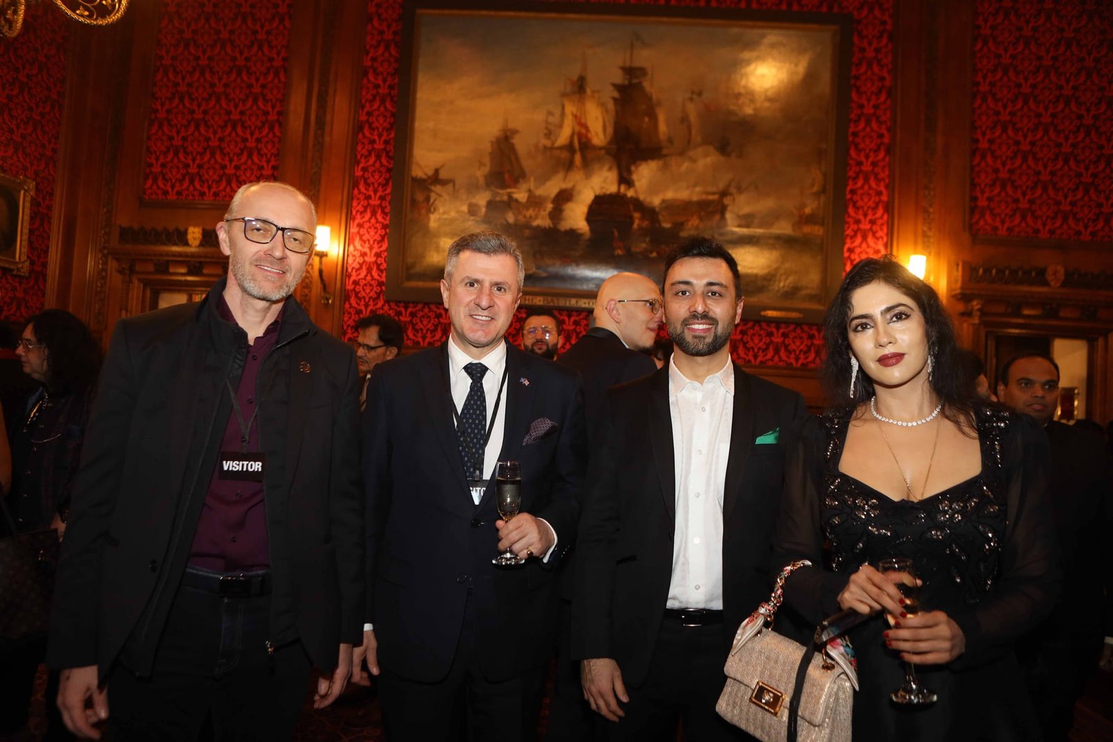 Four guests with champagne beneath the maritime painting at the reception